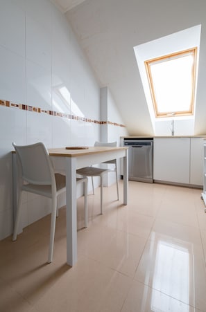 A modern kitchen with a dining area, white cabinetry, a dishwasher, and a skylight. - Baleo Valdoviño Apartment (Valdoviño)