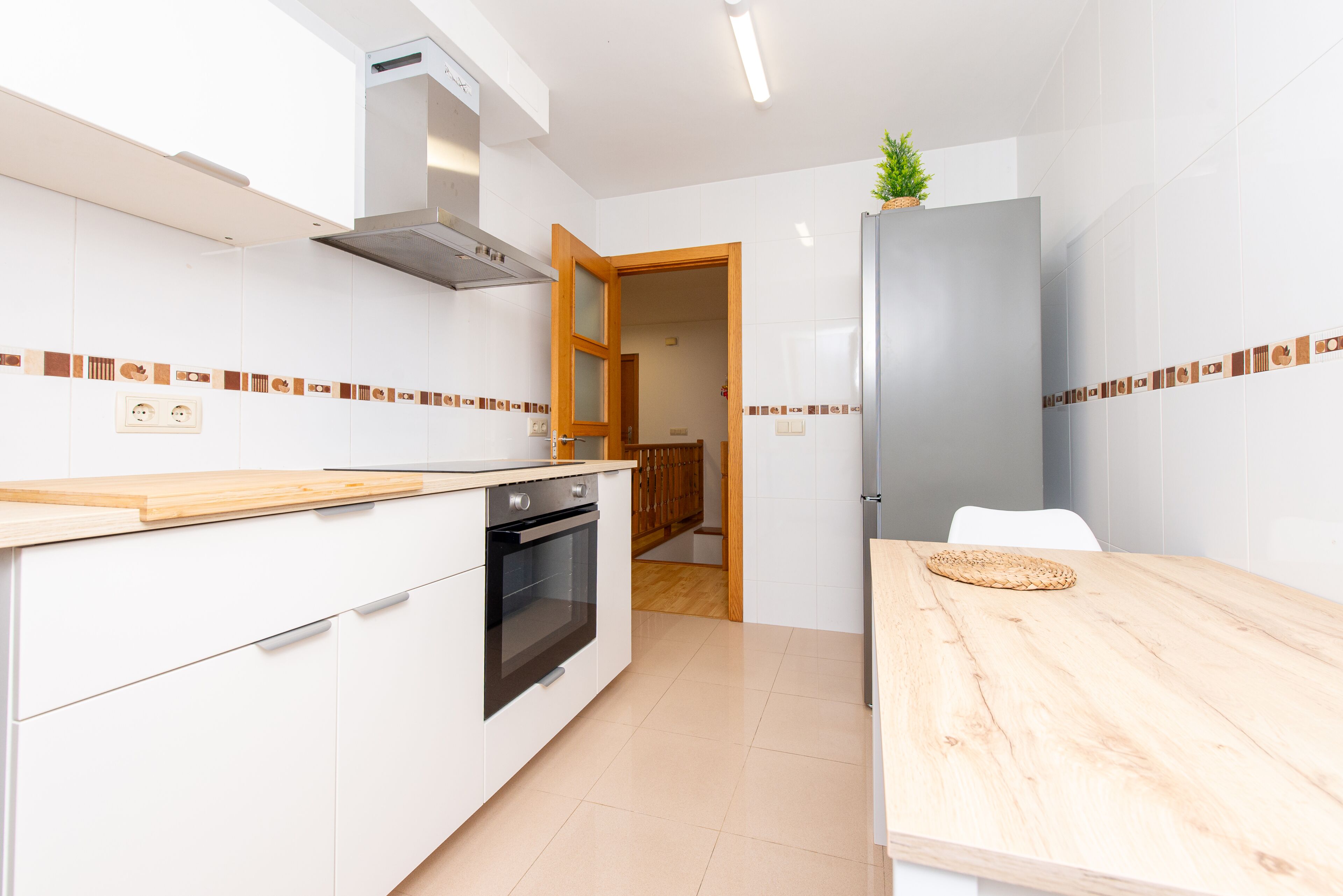 Eine moderne Küche mit weißen Schränken, einer Holz Arbeitsplatte und einem eingebauten Ofen.