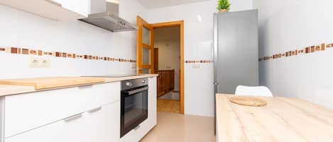 Una cocina moderna con armarios blancos, encimera de madera y horno empotrado.