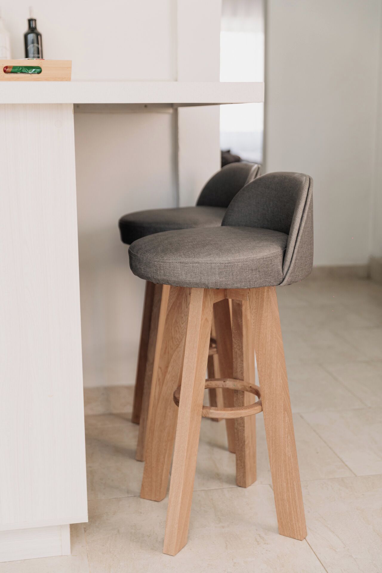 Dos taburetes de bar con patas de madera y asientos tapizados en gris.