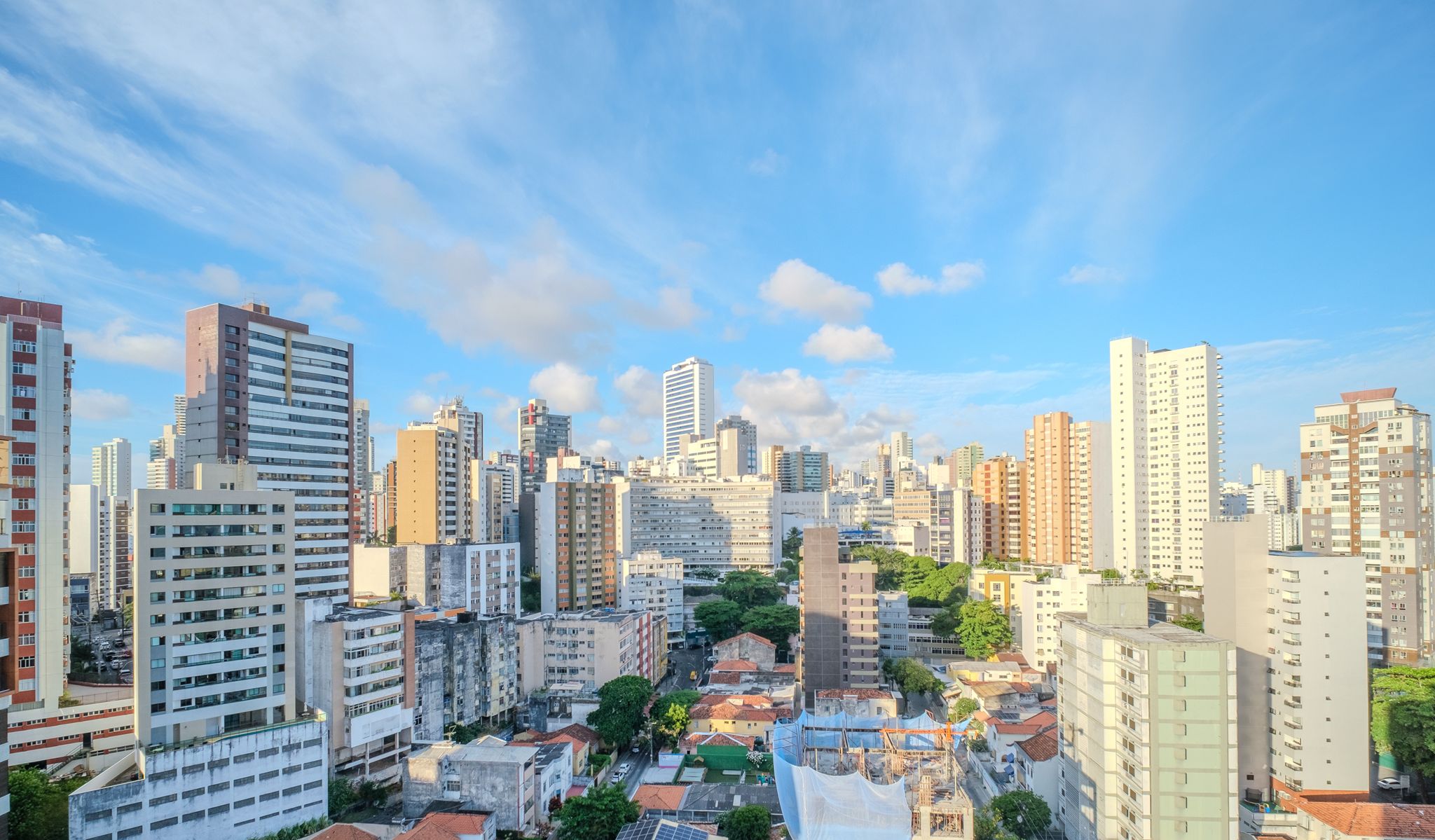 A cityscape with high-rise buildings, a mix of residential and commercial structures, and a clear sky.
