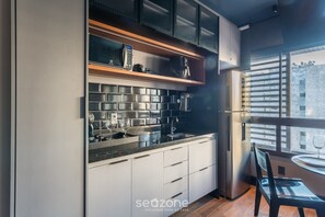 A modern kitchen with a built-in oven, a coffee maker, and a sink. - Studio in Condo w/ Pool in Barra Eub0906 (Salvador)