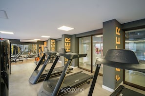Ein Fitnessraum mit Laufbändern, Kraftgeräten und einer Spiegelwand.