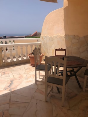 A terrace with a table and chairs, potted plants, and a view of the sea. - Vacation Apartment 'Sotavento' with Sea View, Private Terrace and Wi-Fi (Pájara)