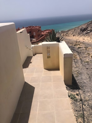 A corridor with numbered blocks leading to a balcony overlooking a beach. - Vacation Apartment 'Sotavento' with Sea View, Private Terrace and Wi-Fi (Pájara)