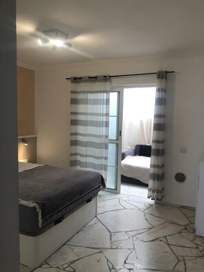 A bedroom with a bed, a nightstand, a ceiling fan, and a sliding glass door leading to another room. - Vacation Apartment 'Sotavento' with Sea View, Private Terrace and Wi-Fi (Pájara)