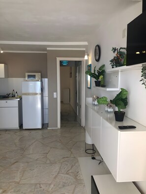 Cuina moderna amb nevera, microones i zona de menjador amb una banca.