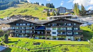 Un hôtel moderne à plusieurs étages, doté de balcons et offrant une vue sur une colline verdoyante.