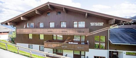 Un edificio de dos pisos con fachada de madera, balcones y un letrero que dice 'HOCHLEGER AM ANGER'.