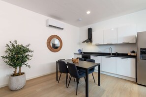 Eine moderne Küche mit weißen Schränken, einer schwarzen Arbeitsplatte und einem Edelstahl-Kühlschrank.
