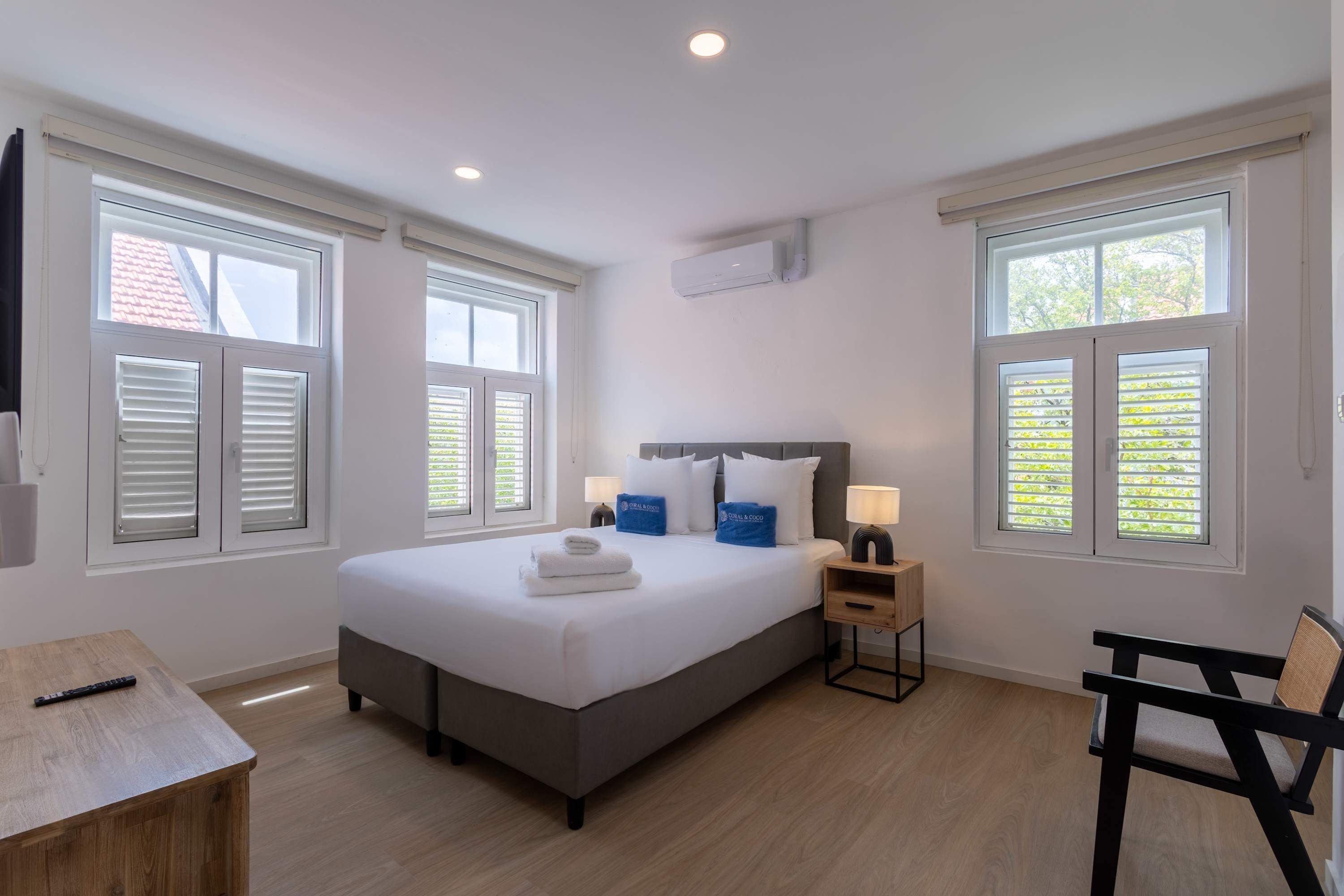 A hotel room with a bed, bedside table, lamp, and a chair.