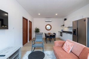Ein kompakter Wohnbereich mit Küchenzeile, Essplatz und einer Sitzecke mit Sofa und Sessel.