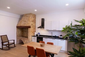 A modern kitchen with white cabinets, a brick oven, and a dining area with a wooden table and orange chairs. - History Comfort Character in Willemstad (Willemstad)