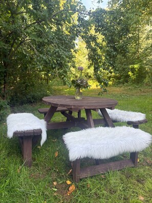 A picnic table with a vase of flowers and fluffy white cushions. - Apartment "Hof Hageneck" with Shared Terrace, Garden, and Wi-Fi (Everswinkel)