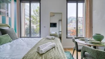 Ein Hotelzimmer mit einem Bett, einem Esstisch und Blick auf die Stadt.
