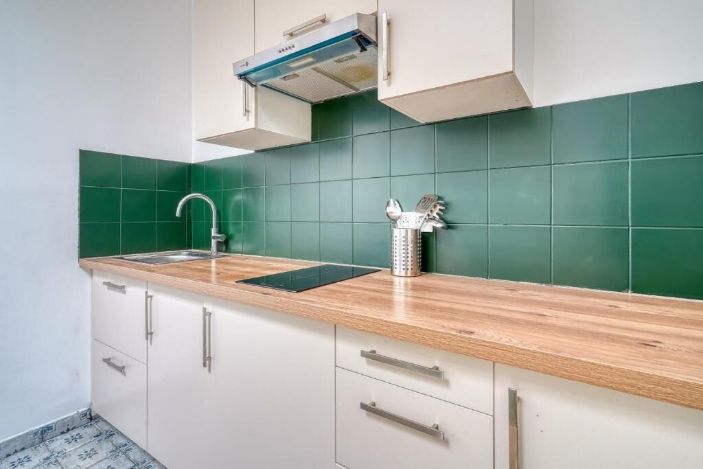 Una cocina con un lavamanos, una tetera de acero inoxidable y un grifo moderno.