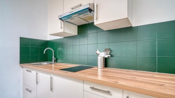 A kitchen with a sink, a stainless steel kettle, and a modern faucet.