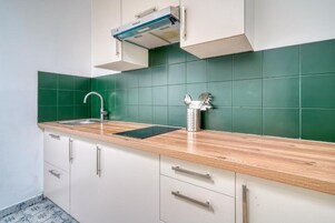 Una cocina con un lavamanos, una tetera de acero inoxidable y un grifo moderno.