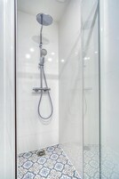 Ducha moderna con cabezal de ducha de mano y panel de control en la pared.