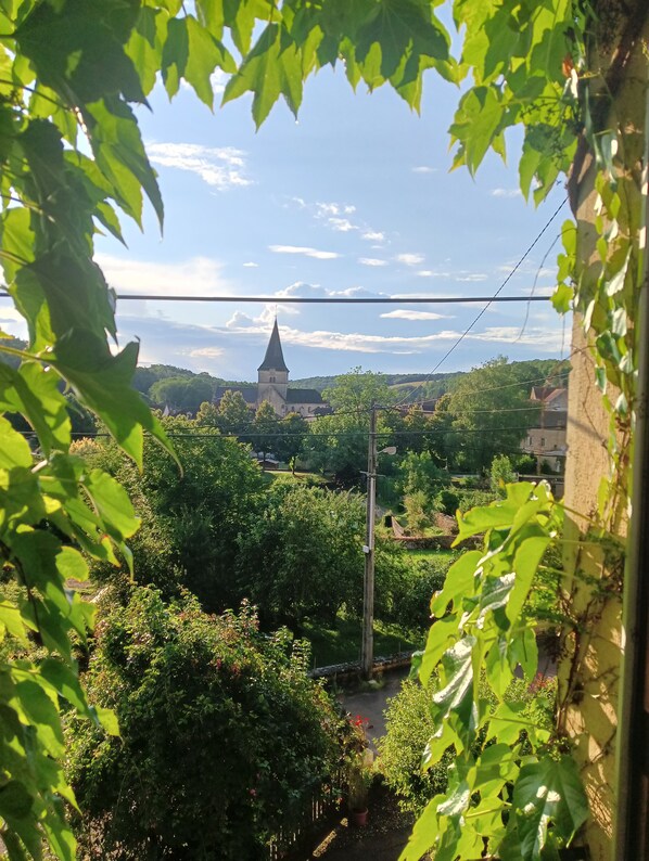 Vista de una iglesia con una aguja, rodeada de exuberante vegetación y edificios residenciales.
