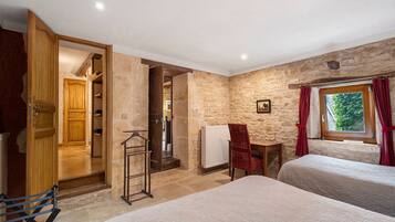 A bedroom with two beds, a wooden wardrobe, a radiator, and a window with curtains.