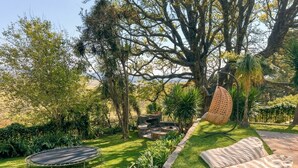 Un giardino con un trampolino, un'area salotto e un albero grande.