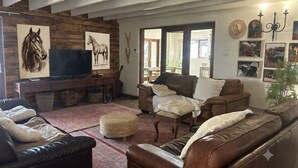 Un soggiorno con camino, divani in pelle, televisione e opere d'arte alle pareti.