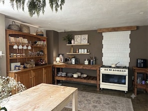 A kitchen with wooden cabinets, a stove, and various kitchen items. - Large Family Villa with Swimming Pool on the Panorama Route close to Kruger Park (Graskop)