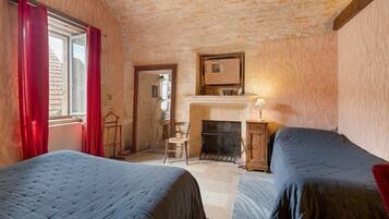 Une chambre avec deux lits, une cheminée et un miroir au mur.