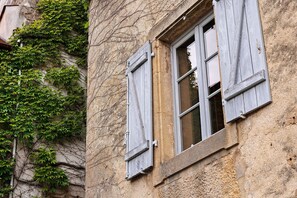 A building with ivy-covered walls and a window with wooden shutters.