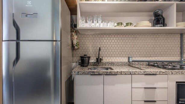 Een moderne keuken met een roestvrijstalen koelkast, een granieten aanrechtblad en een backsplash van hexagontegels.
