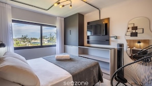 Een moderne hotelkamer met een bed, een televisie, een bureau en uitzicht op de omgeving.