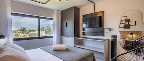 A modern hotel room with a bed, a TV, a desk, and a view of the outdoors.