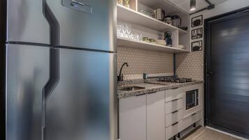 Cucina moderna con frigorifero in acciaio inossidabile, piano di lavoro in granito, forno integrato e una porta nera.