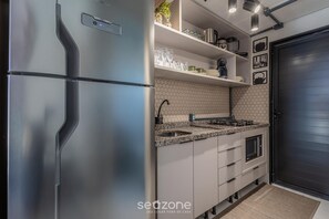 Una cocina moderna con refrigerador de acero inoxidable, encimera de granito, horno empotrado y puerta negra.