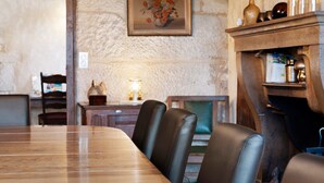 Uma área de refeições com uma mesa de madeira comprida e cadeiras de couro.