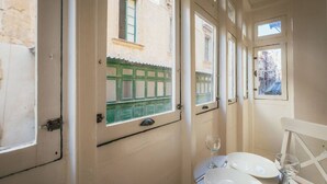 A narrow corridor with a window overlooking a building with a green facade. - Casa Due Balli | 400-Year Historic Valletta House (Valletta)