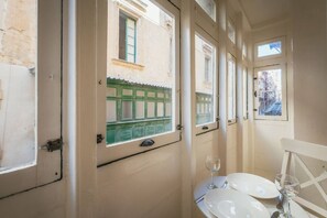 A narrow corridor with a window overlooking a building with a green facade. - Casa Due Balli | 400-Year Historic Valletta House (Valletta)