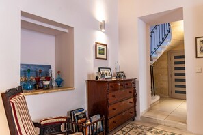 A hallway with a wooden dresser, a framed picture, and a staircase with a metal railing. - Casa Due Balli | 400-Year Historic Valletta House (Valletta)