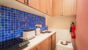 A compact kitchenette with a blue-tiled backsplash, a toaster, a kettle, a coffee maker, and a small refrigerator. - Casa Due Balli | 400-Year Historic Valletta House (Valletta)
