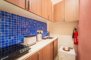 A compact kitchenette with a blue-tiled backsplash, a toaster, a kettle, a coffee maker, and a small refrigerator. - Casa Due Balli | 400-Year Historic Valletta House (Valletta)