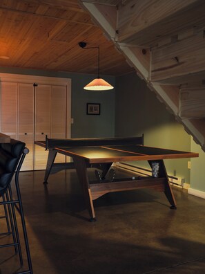 A pool table in a room with wooden beams on the ceiling, a hanging pendant light, and a framed picture on the wall. - Evergreen Overlook—elevated Catskills cabin—cedar hot tub, sauna, gym, rec room (Parksville)
