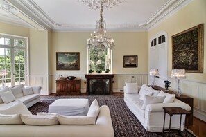A spacious living room with a chandelier, two sofas, a fireplace, and artwork on the walls. - Classic South of France elegances set in an oasis in the heart of Cannes (Cannes)