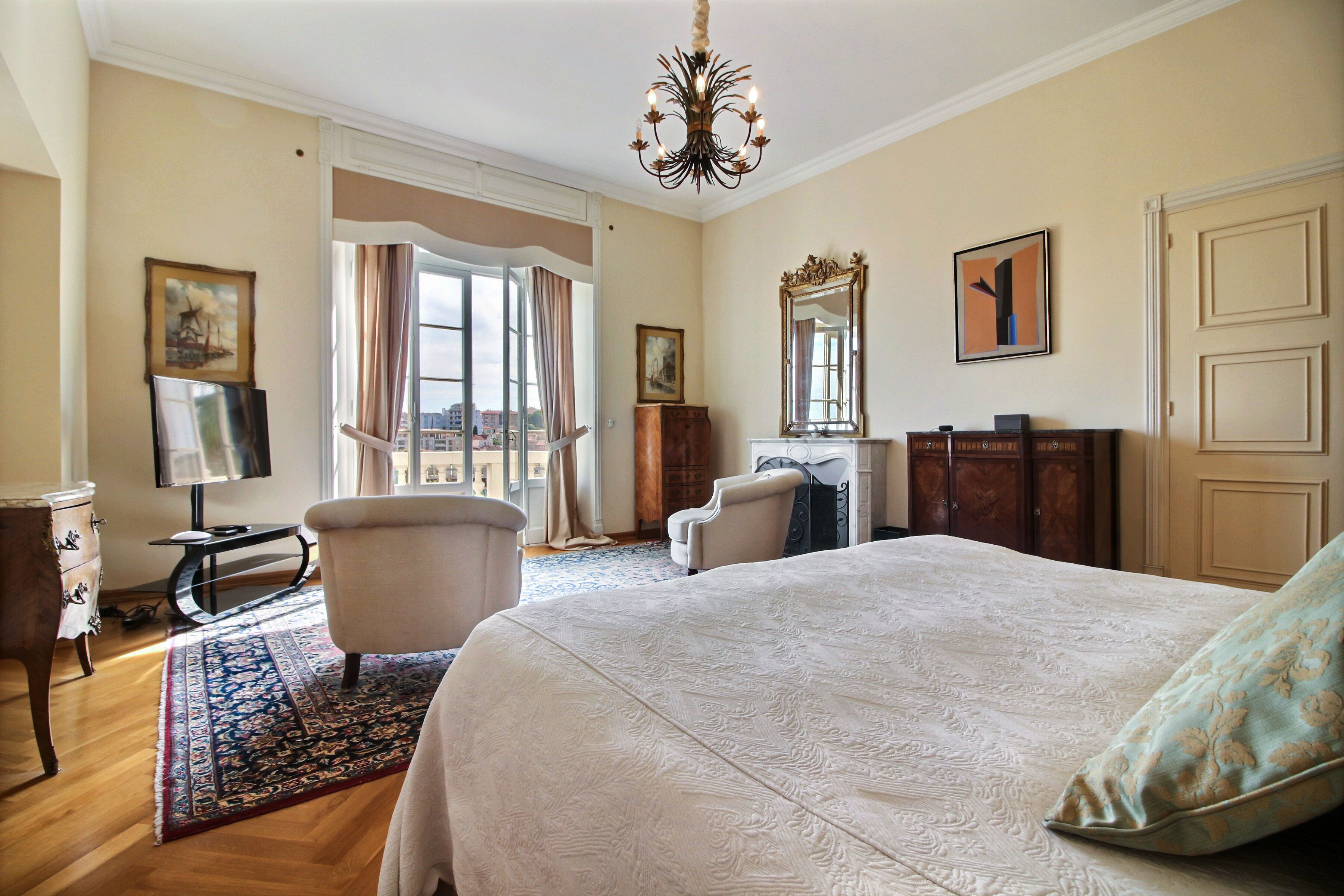 A hotel room with a large bed, a desk, a chair, a dresser, and a window with curtains.