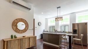 A modern kitchen with a wooden console, a round mirror, a hanging light fixture, and a stainless steel refrigerator. - NEW Beautifully Restored Historic Apartment (Willemstad)