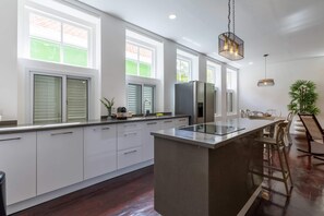 A modern kitchen with a central island, large windows, and a dining area with chairs. - NEW Beautifully Restored Historic Apartment (Willemstad)