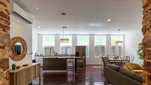 A spacious kitchen with a central island, a dining area with a sofa, and a living room with a large window. - NEW Beautifully Restored Historic Apartment (Willemstad)