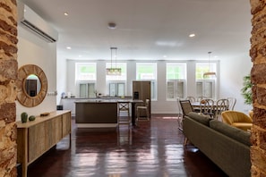 A spacious kitchen with a central island, a dining area with a sofa, and a living room with a large window. - NEW Beautifully Restored Historic Apartment (Willemstad)