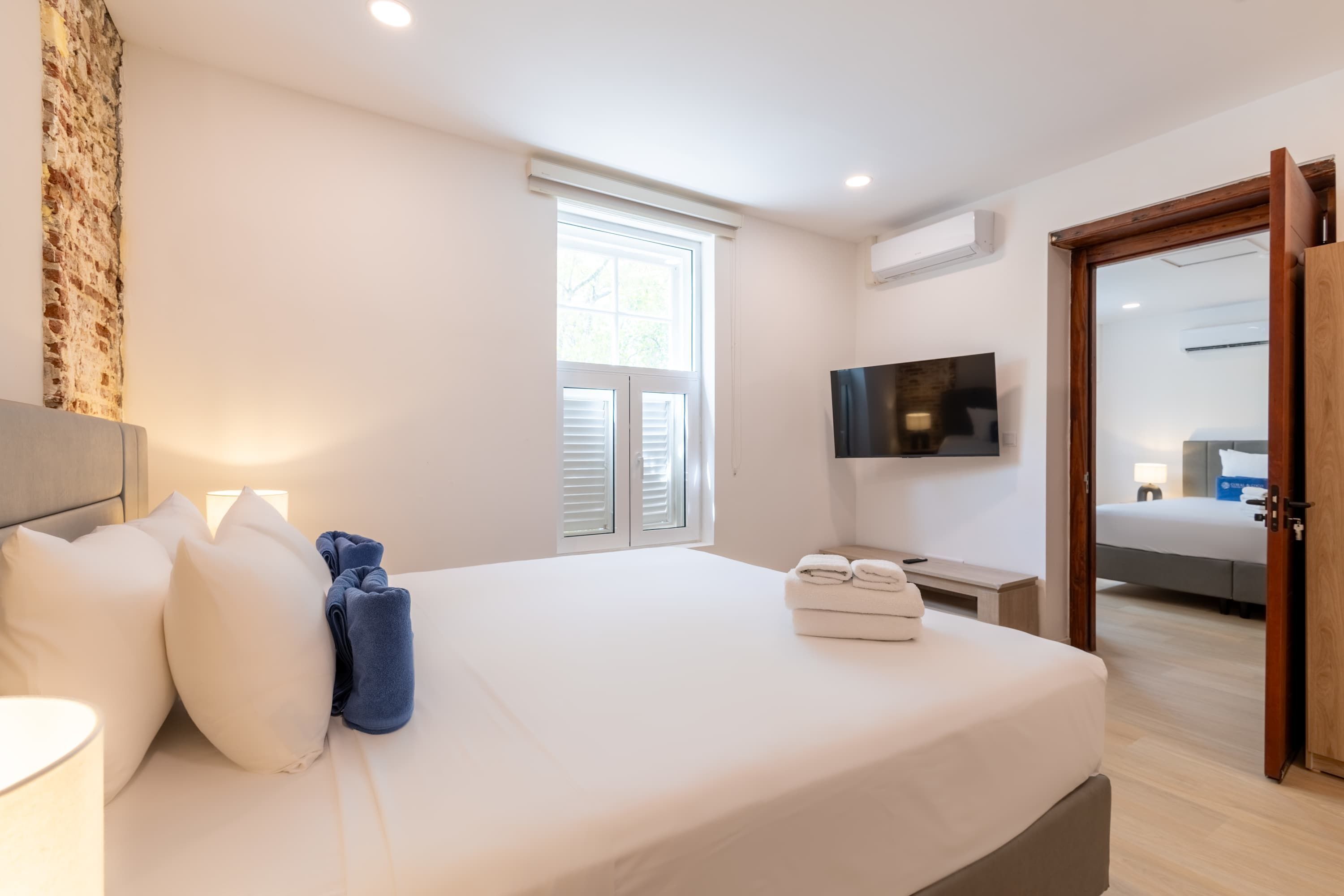 Ein Hotelzimmer mit Bett, Fernseher, Fenster und Tür.