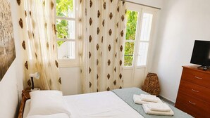 A hotel room with a bed, a TV, a dresser, and a window with curtains. - Kalymnos Island Gentaway - Chora Central Location (Kalymnos)